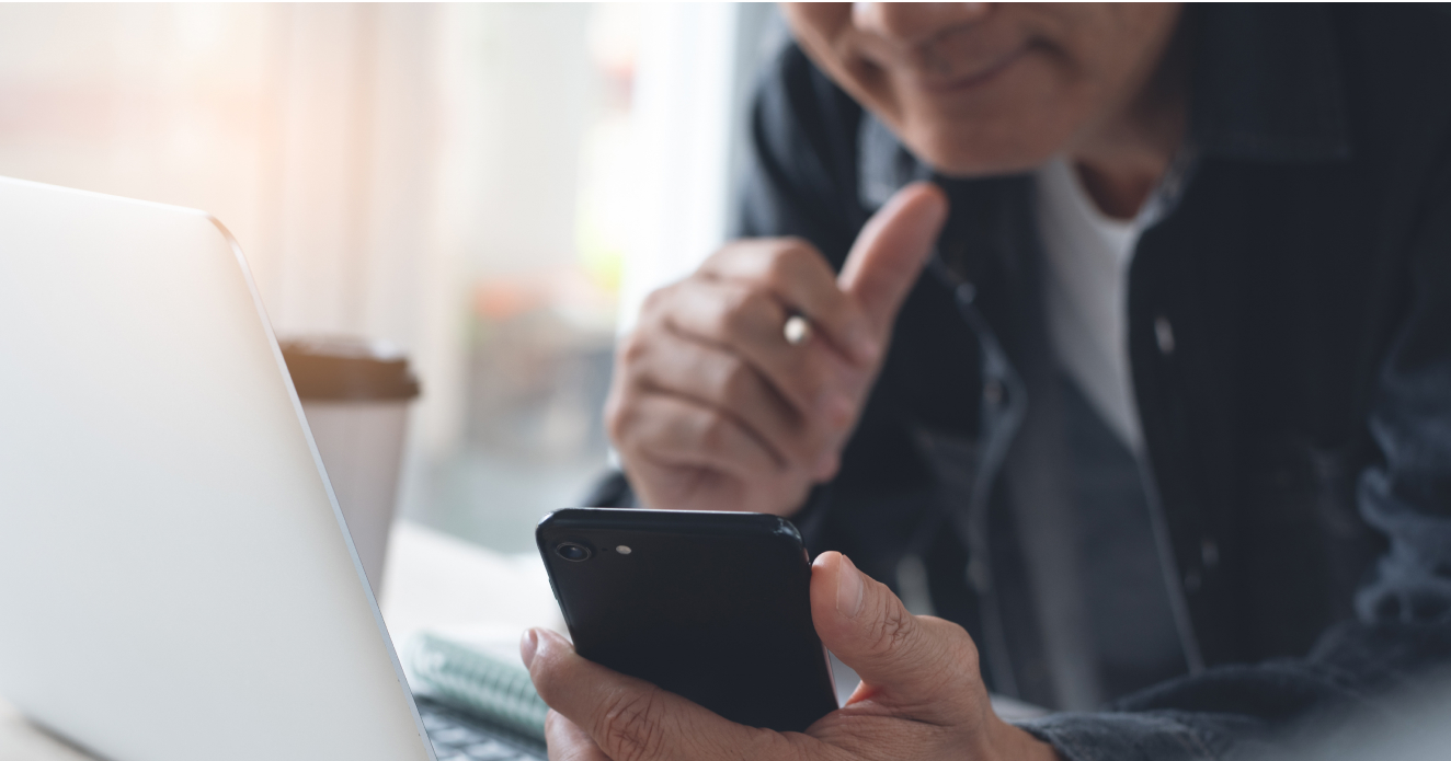 A closeup view of a person using their phone next to their computer.